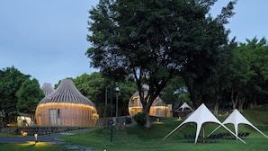 A series of spherical treehouses with a pathway leading to them, surrounded by lush greenery and a clear sky. - Heart Retret Seasons Village (Foshan)