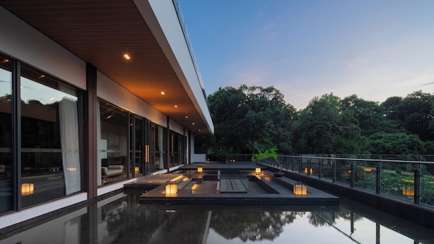 A modern building with large windows, a reflective pool, and outdoor seating. - Heart Retret Seasons Village (Foshan)