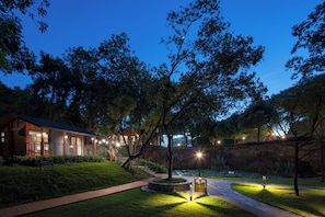 Un espacio exterior bien iluminado con un sendero, un jardín circular y un edificio con múltiples ventanas.