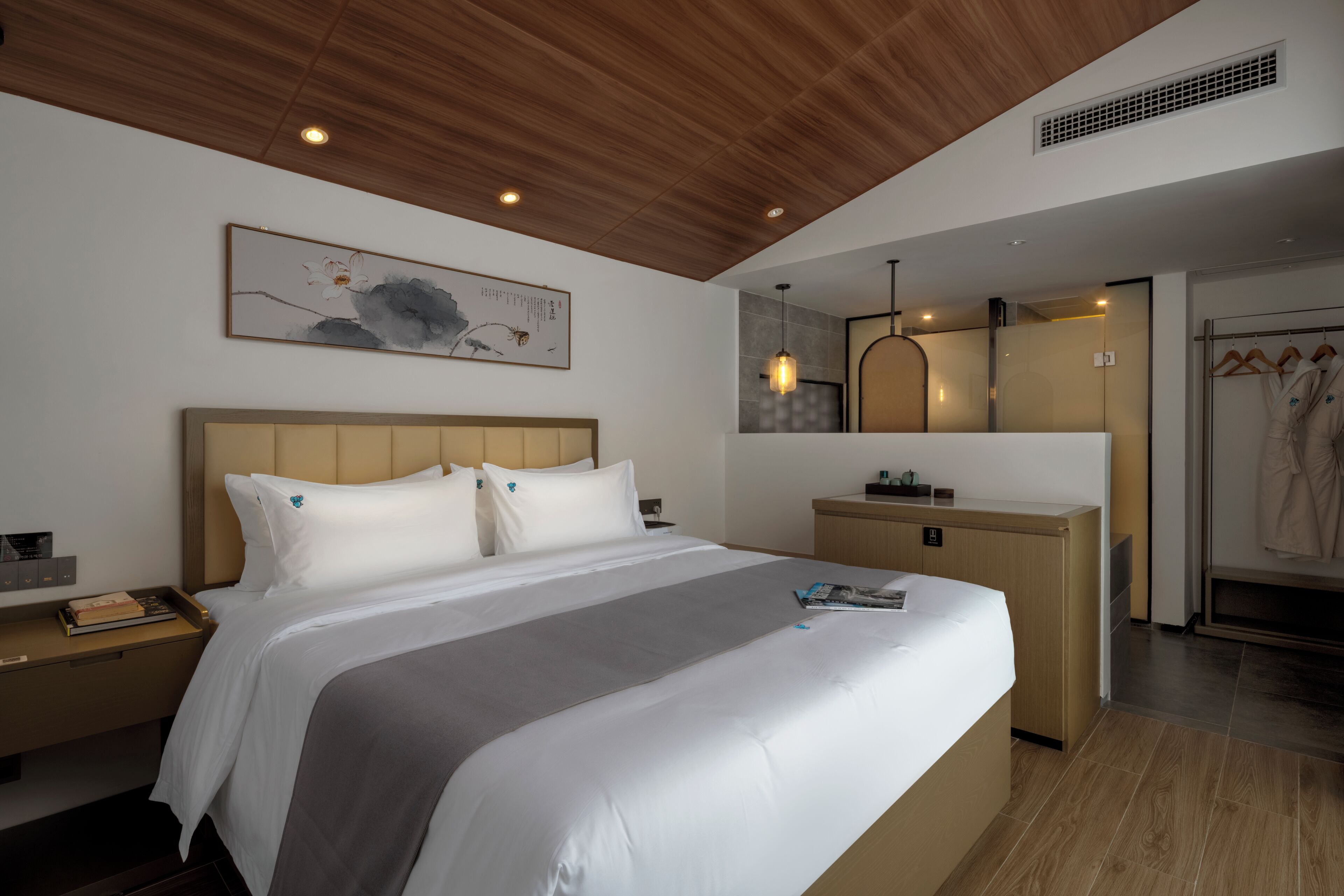A modern hotel room with a large bed, wooden ceiling, a painting, a bedside table, a nightstand, a dresser, and a mirror.