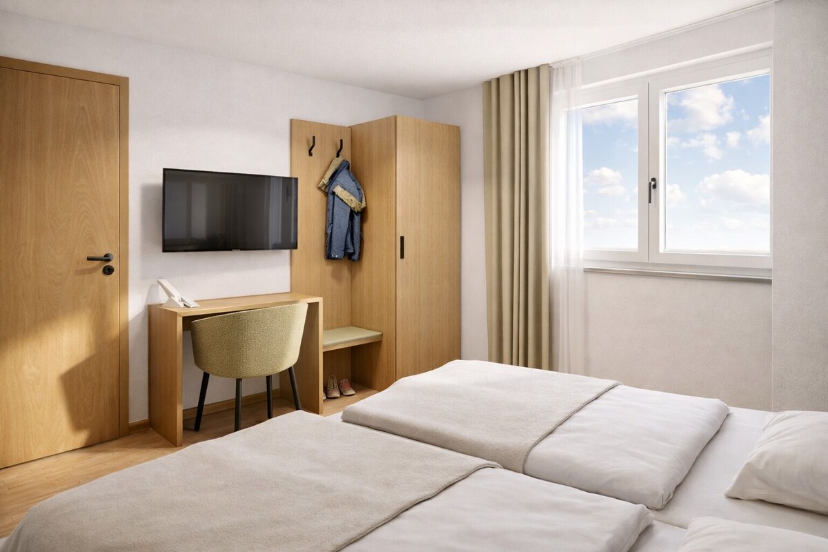 A hotel room with two beds, a desk, a TV, and a wardrobe.