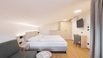 Ein modernes Hotelzimmer mit Bett, Schreibtisch, Stuhl und kleinem Tisch.