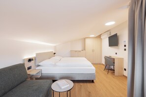A modern hotel room with a bed, a desk, a chair, and a small table. - odilum (Mondsee)