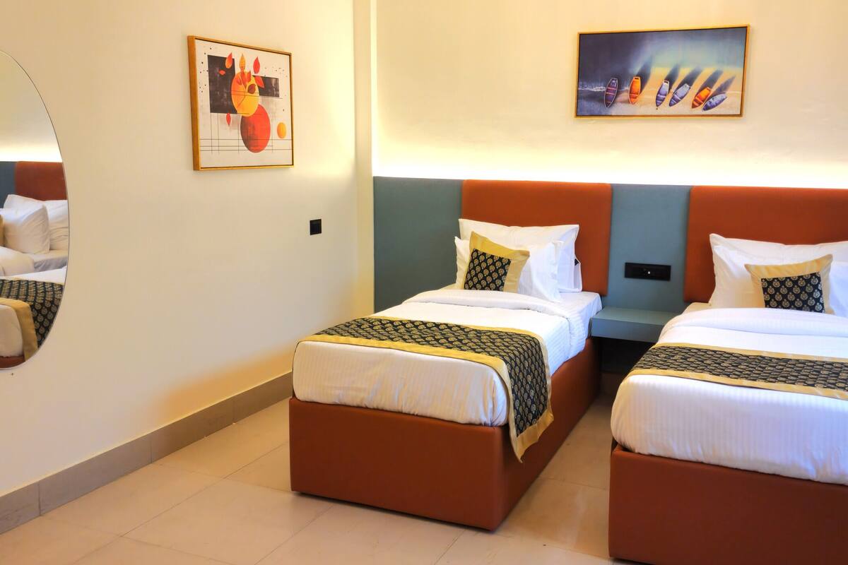 A hotel room with two beds, a large mirror, and artwork on the walls.
