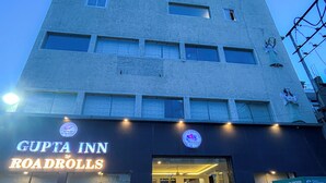 Un edificio con un letrero que dice 'GUPTA INN By RoadRolls' y una motocicleta estacionada adelante.