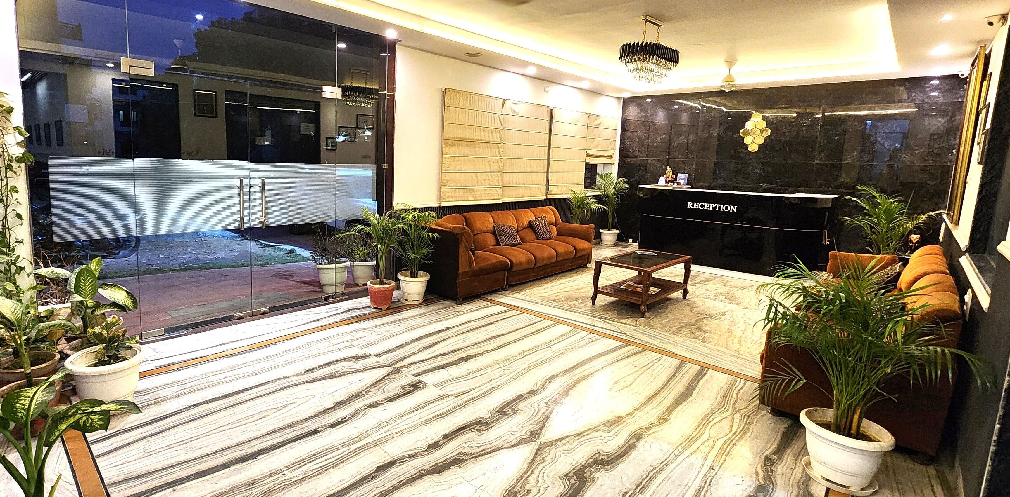 A modern reception area with a marble floor, a reception desk, a brown sofa, and potted plants.