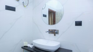 Un baño con un lavamanos blanco, un espejo redondo y un dispensador de toallas.