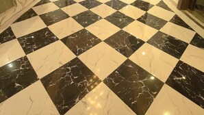 Una habitación amplia con piso de diseño de cuadros, techo de vidrio y una gran lámpara de candelabro.