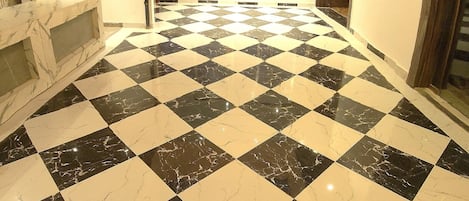 A spacious room with a checkered floor, a glass ceiling, and a large chandelier.