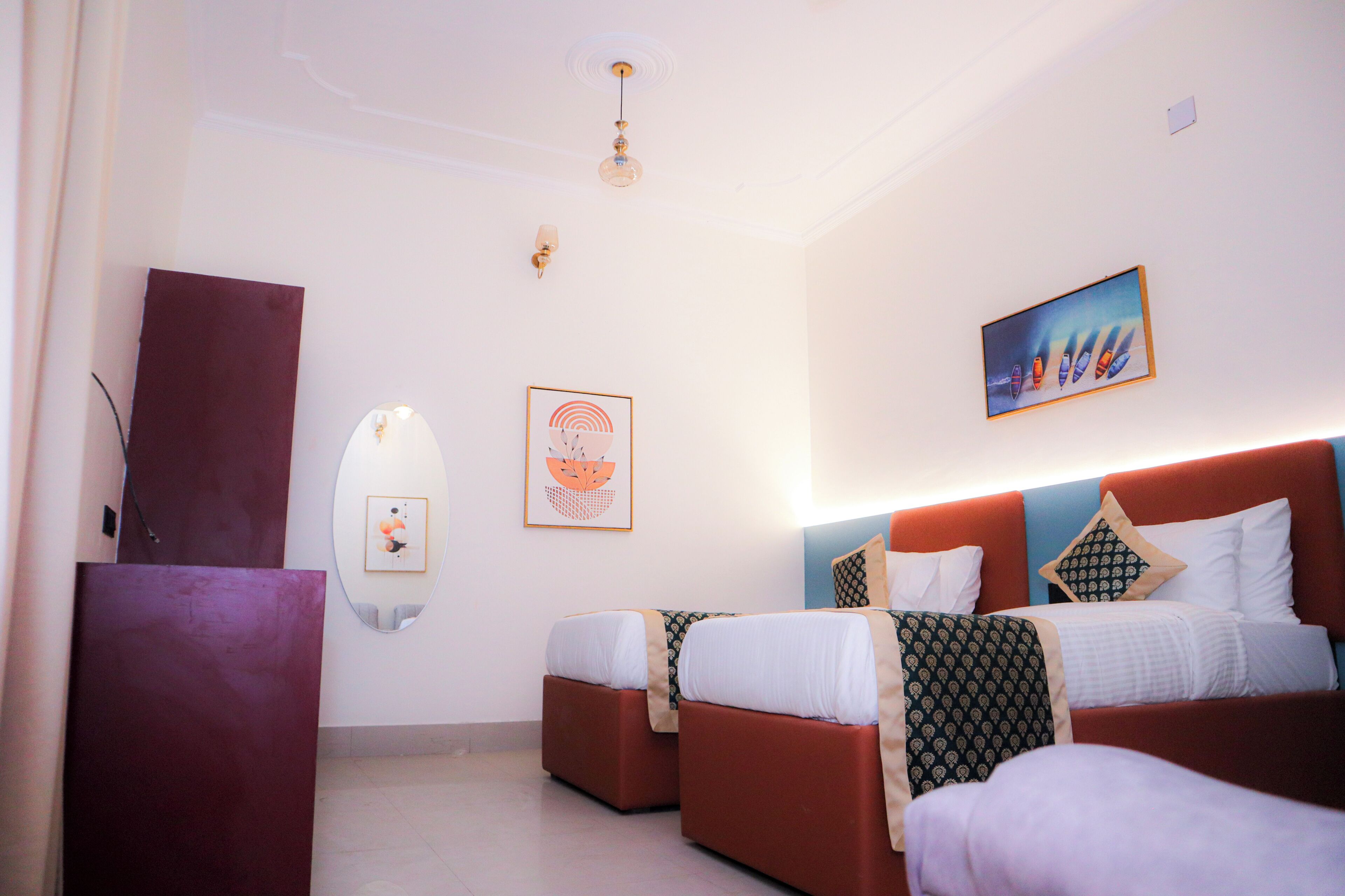 Habitación de hotel con dos camas, un escritorio y obras de arte en las paredes.