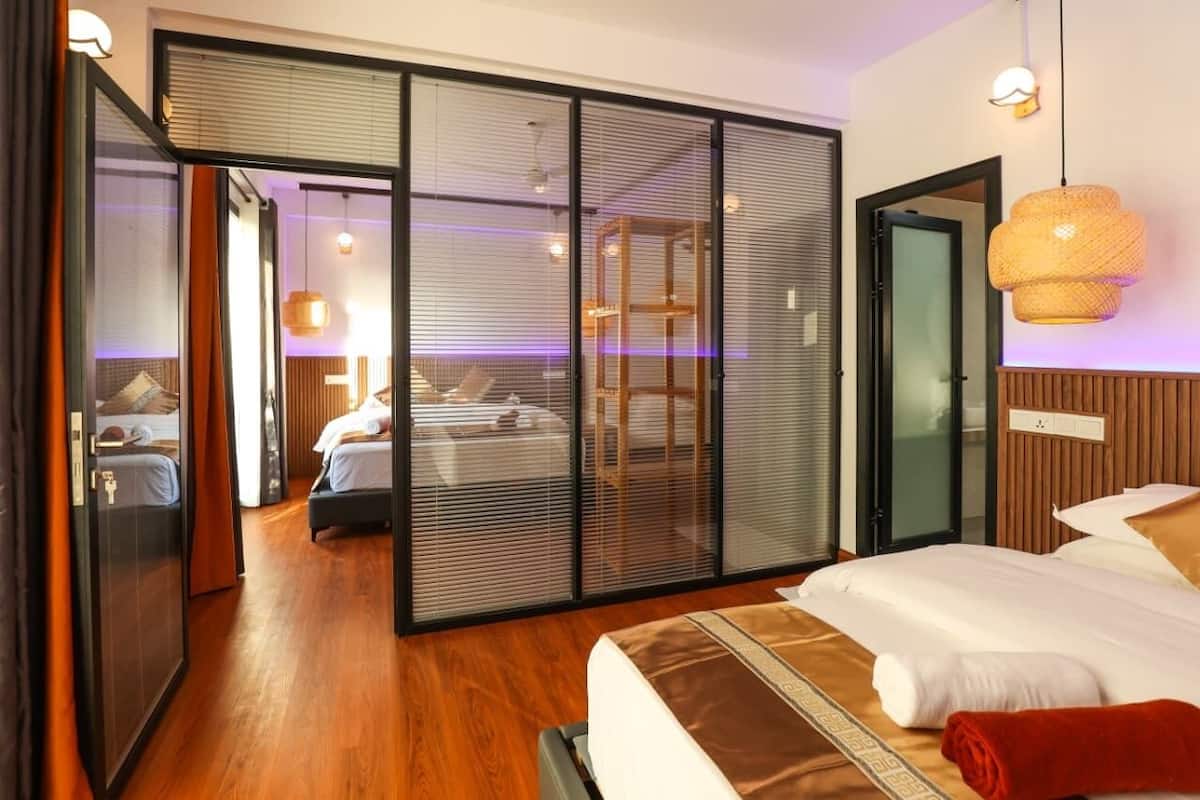 Ein Hotelzimmer mit einer großen Schiebetür, einem Bett mit weißen Bettwäsche, einem Holzboden und einer hängenden Leuchte.
