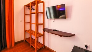 A room with a wooden shelving unit, a mounted TV, and a desk with a computer. - Island Vista Thoddoo (Thoddoo)