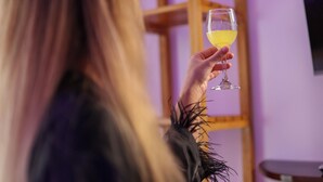 A person holding a glass of drink in a room with a wooden shelf and a wall-mounted TV. - Island Vista Thoddoo (Thoddoo)