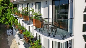 A modern building with multiple balconies, each equipped with glass railings and outdoor furniture. - Island Vista Thoddoo (Thoddoo)