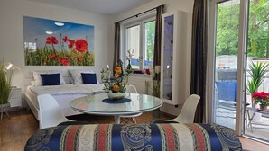 Un salon moderne avec un canapé, une table basse en verre et un tableau représentant des fleurs rouges.