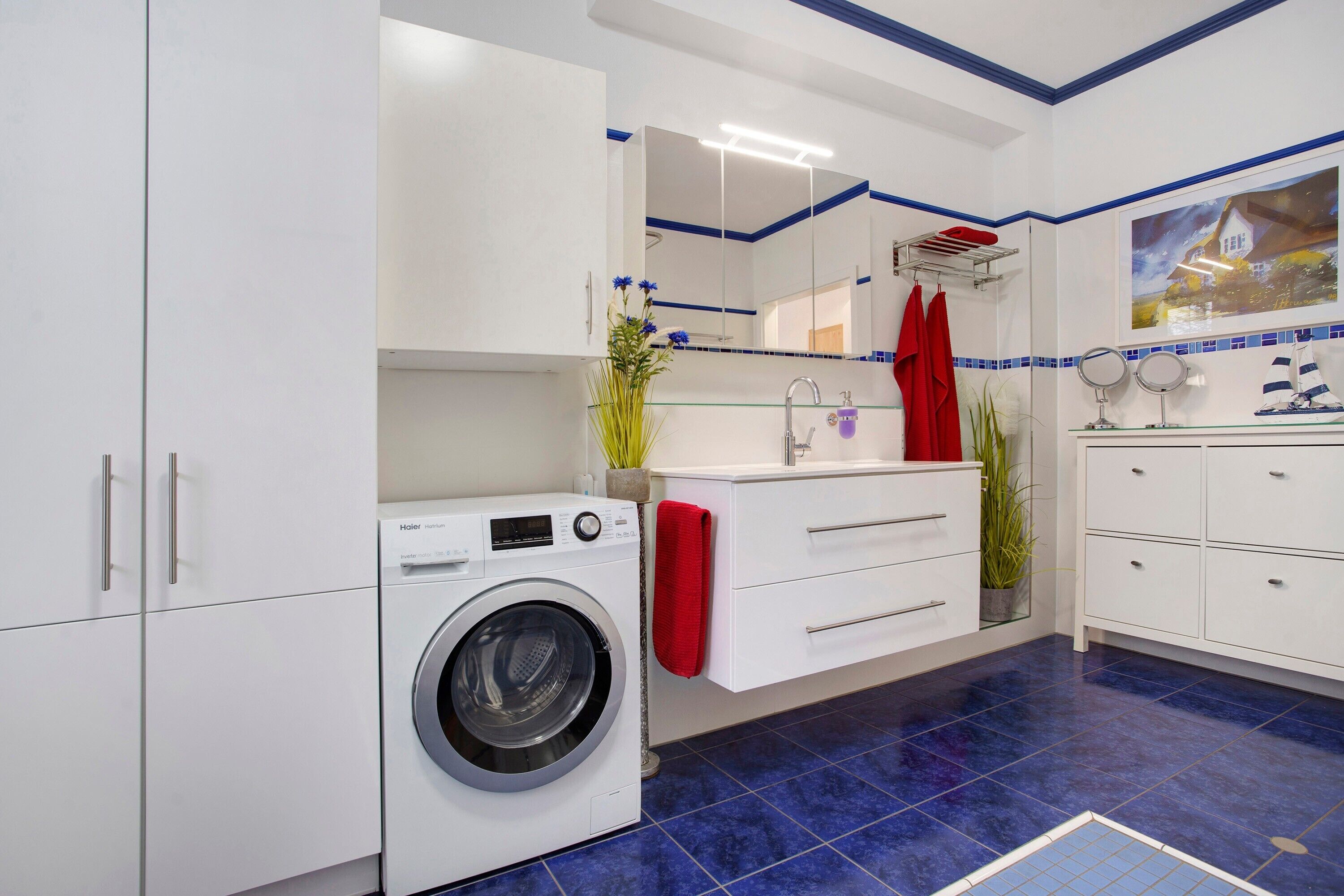 A modern bathroom with a washing machine, a glass sink, and a mirror.