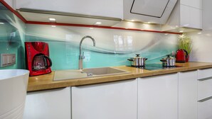 Une cuisine moderne avec un évier en acier inoxydable, une machine à café rouge et une plante en pot.