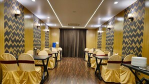 A conference room with a herringbone wood floor, tables with chairs, and patterned walls. - VN Alpha Suites (Bengaluru)