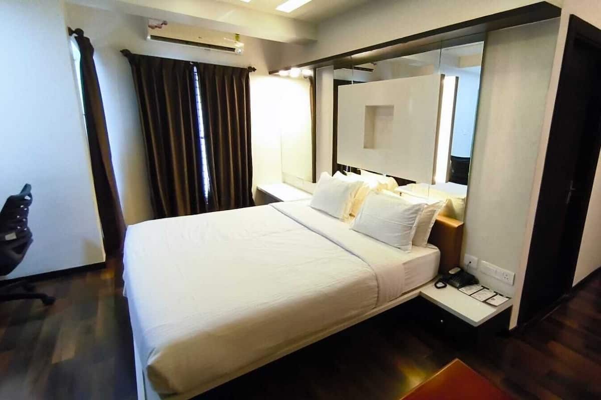 A hotel room with a bed, a bedside table, a mirror, and a door.