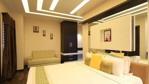 A hotel room with a bed, a sofa, a wardrobe, and a large mirror. - VN Alpha Suites (Bengaluru)