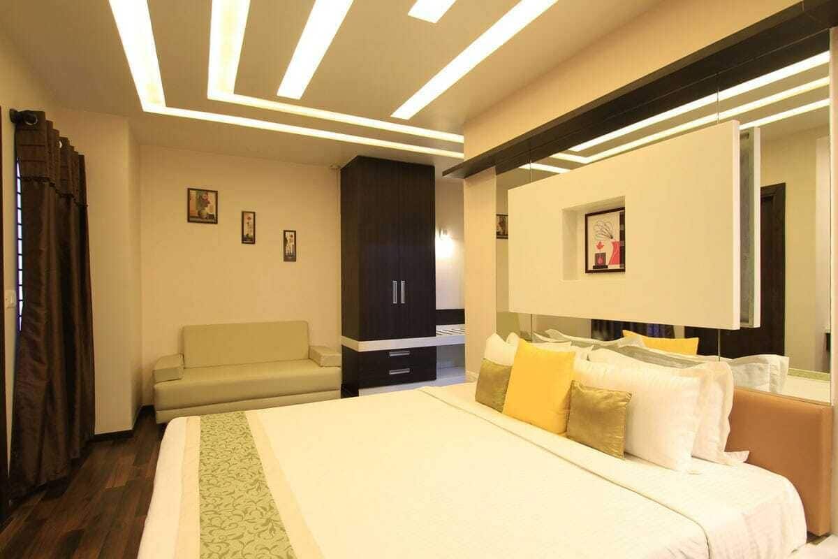 A hotel room with a bed, a sofa, a wardrobe, and a large mirror.