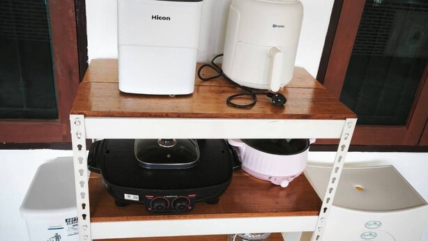 A white shelf with a coffee maker, a toaster, and a portable speaker.