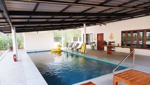 An indoor swimming pool with a covered area, a fire extinguisher, a duck float, and a surfboard.
