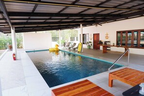 An indoor swimming pool with a covered area, a fire extinguisher, a duck float, and a surfboard. - Pran Botanica Private Pool Villa (Pranburi)