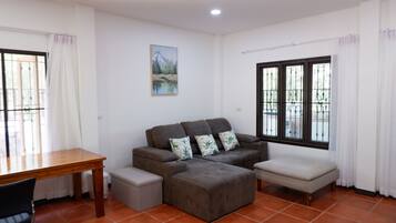 A living room with a sofa, ottoman, and a wooden table.