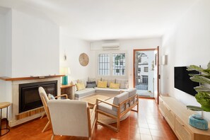 Una sala de estar con chimenea, un conjunto de sofás, una televisión y un ventanal grande.