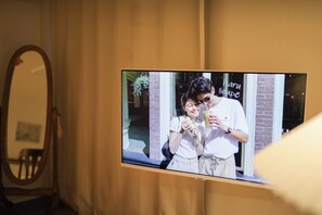 A television mounted on a wall displaying a couple holding drinks. - JS building-502 (Seoul)