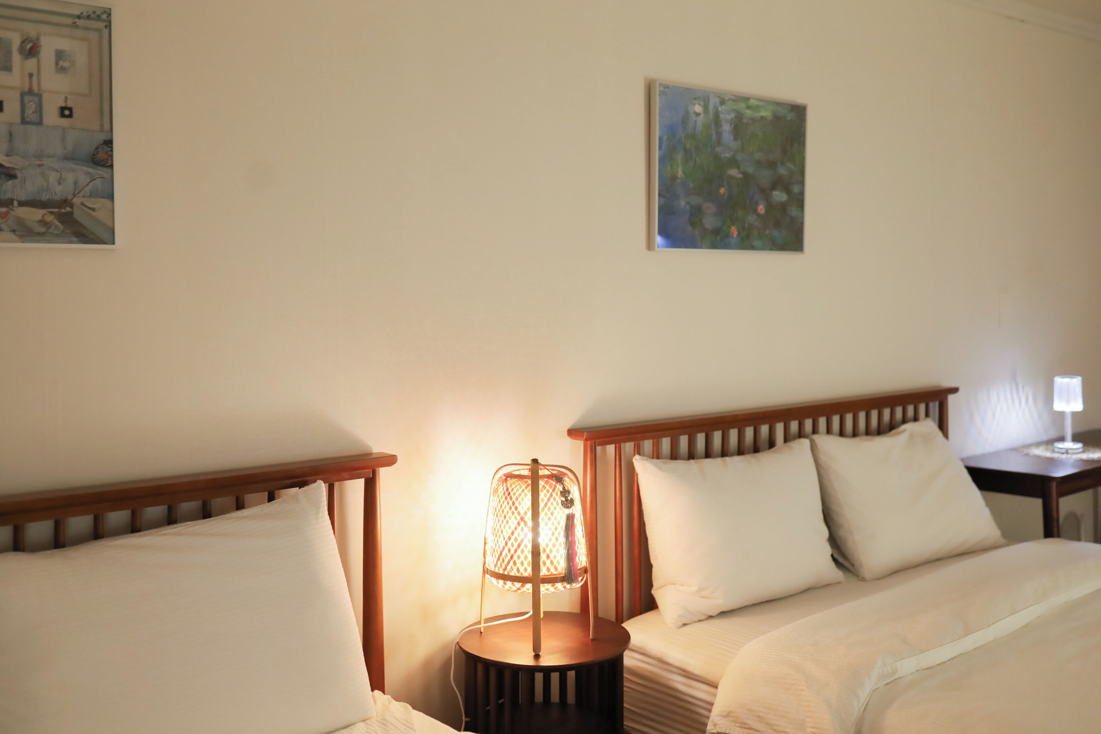 Une chambre d’hôtel avec deux lits, une table de chevet avec une lampe et un tableau au mur.