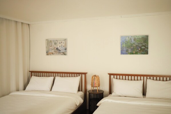 Une chambre d’hôtel avec deux lits, une table de chevet et deux tableaux accrochés au mur.