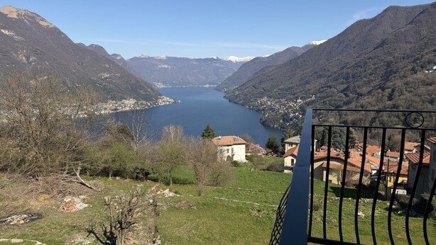 A mountainous landscape with a lake, a small settlement, and a building with a red roof. - Enchantment of the Lake - app Cernobbio Two-room apartment with A / C (Molina)