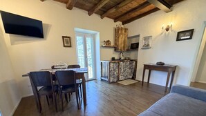 A dining area with a table and chairs, a kitchen with a sink and cabinets, and a gray sofa. - Enchantment of the Lake - app Cernobbio Two-room apartment with A / C (Molina)
