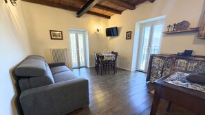A living room with a sofa, a dining table with chairs, a TV, and a fireplace. - Enchantment of the Lake - app Cernobbio Two-room apartment with A / C (Molina)