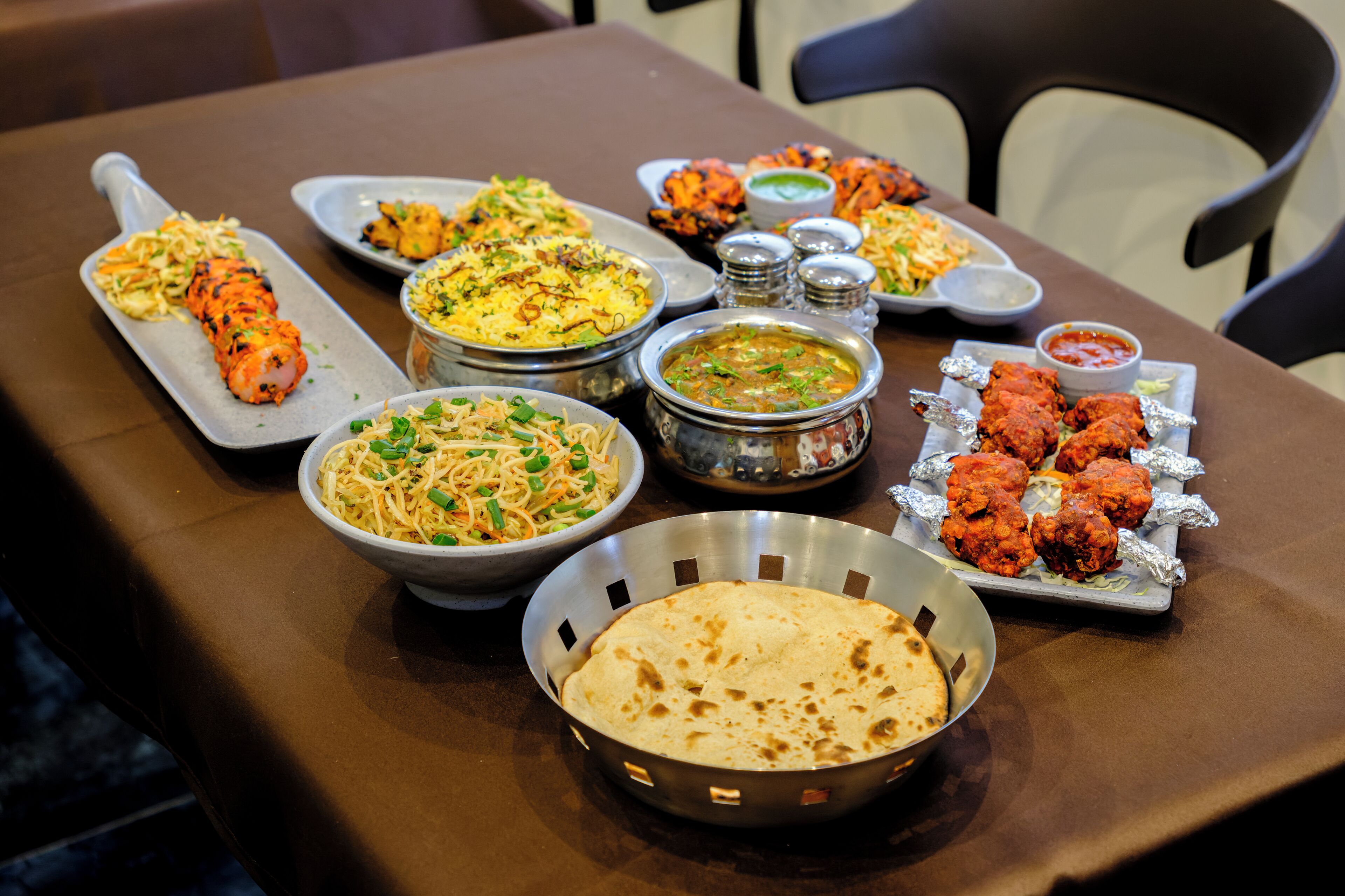 Una mesa con varios platos, incluyendo una samosa, pan naan y un tazón de sopa.