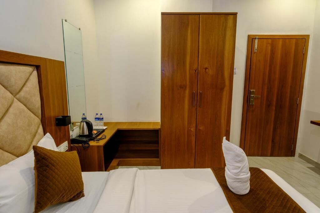 A hotel room with a bed, a desk, a wardrobe, and a mirror.