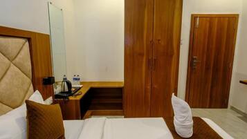 A hotel room with a bed, a desk, a wardrobe, and a mirror.