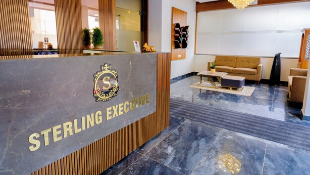 Una reception con un logo e la scritta 'STERLING EXECUTIVE' su una superficie in marmo. Sullo sfondo, un divano e un tavolino da caffè.