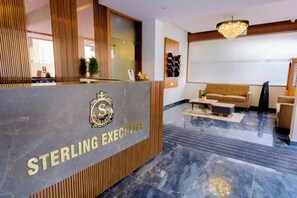 Ein Empfangstresen mit einem Logo und der Aufschrift 'STERLING EXECUTIVE' auf einer Marmorplatte. Im Hintergrund befinden sich ein Sofa und ein Couchtisch.