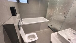 Moderni kylpyhuone, jossa on kylpyamme, wc ja pesuallas.