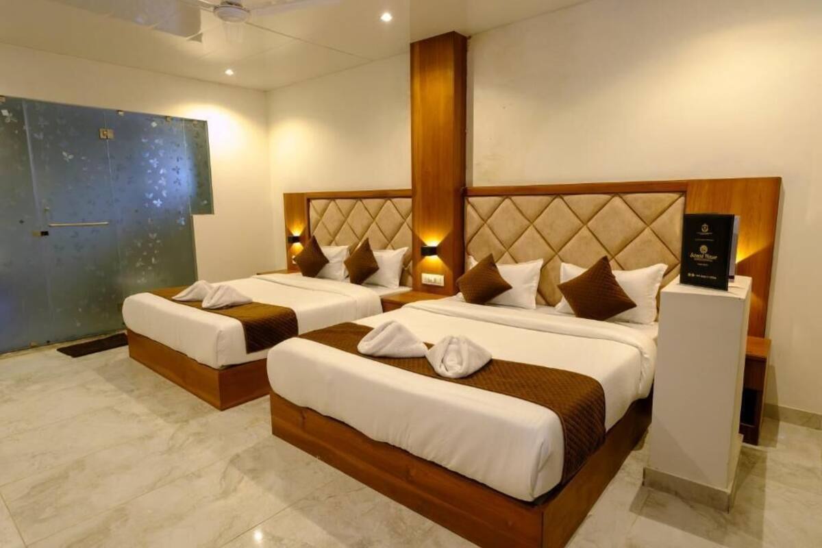 Quarto de hotel com duas camas, cabeceira de madeira, luminárias de cabeceira e minibar.