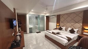 Camera d'albergo moderna con un grande letto, televisione, angolo caffè e cabina doccia in vetro.