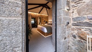 A bedroom with a stone wall, a bed, and a wooden ceiling beam. - Hotel Sarela Natura (Santiago de Compostela)
