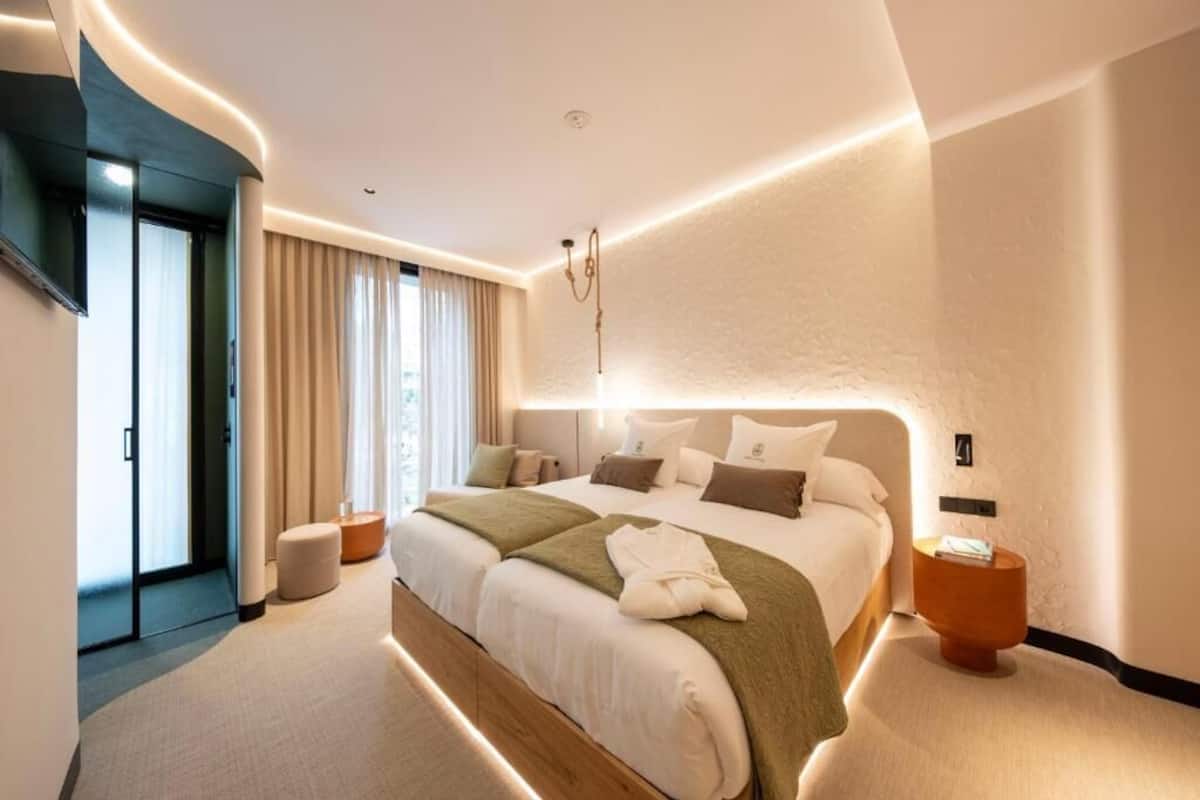 A modern hotel room with a large bed, a flat-screen TV, a bedside table, and a sliding door leading to a balcony.