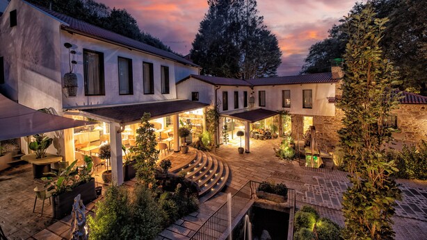A courtyard with outdoor seating, stone pathways, and a building with multiple windows. - Hotel Sarela Natura (Santiago de Compostela)