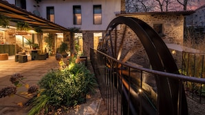 A courtyard with a water wheel, stone buildings, and potted plants. - Hotel Sarela Natura (Santiago de Compostela)