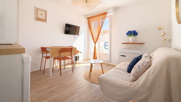 A compact living space with a dining area, a sofa, a TV, and a ceiling fan. - Charming appartment La Pironnière - Les Sables - 4 people (Les Sables-d´Olonne)