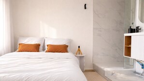 A hotel room with a bed, a nightstand, a mirror, and a marble bathroom. - Charming appartment La Pironnière - Les Sables - 4 people (Les Sables-d´Olonne)